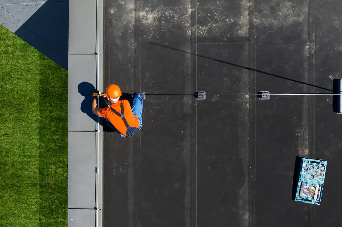 Rope-access roofing technician working on the exterior of a commercial building